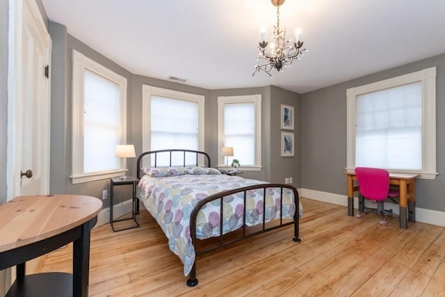 bedroom featuring light wood-type flooring, an inviting chandelier, and multiple windows