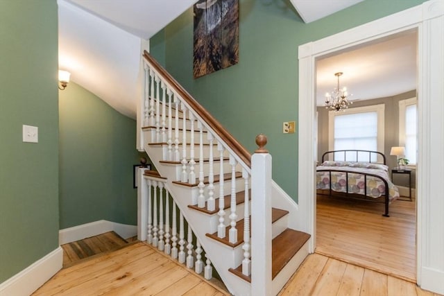 stairs with hardwood / wood-style floors and a notable chandelier