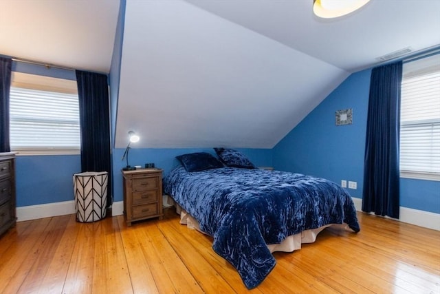 bedroom with vaulted ceiling, wood-type flooring, and multiple windows