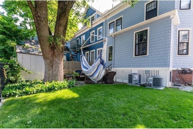 back of property featuring a lawn and central air condition unit