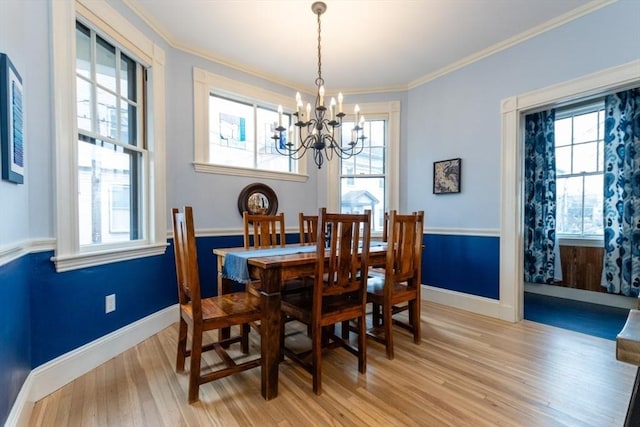 dining area with light hardwood / wood-style flooring, crown molding, and a notable chandelier