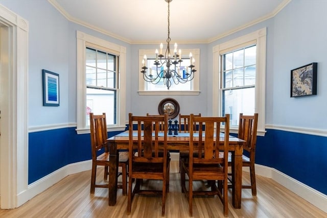 dining room featuring light wood-type flooring, a wealth of natural light, an inviting chandelier, and ornamental molding