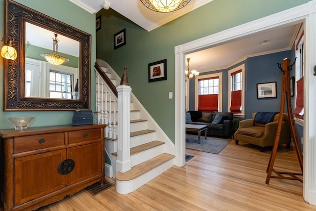 stairs with crown molding, a chandelier, and hardwood / wood-style flooring