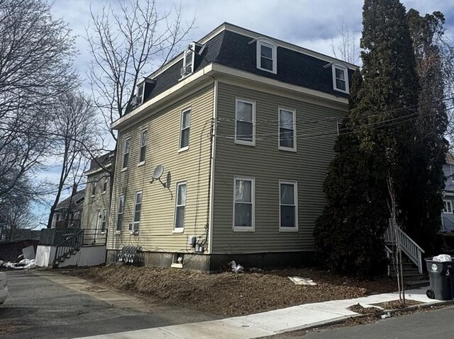 view of side of property with mansard roof and roof with shingles