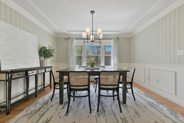dining space with an inviting chandelier, a decorative wall, a wainscoted wall, and wood finished floors