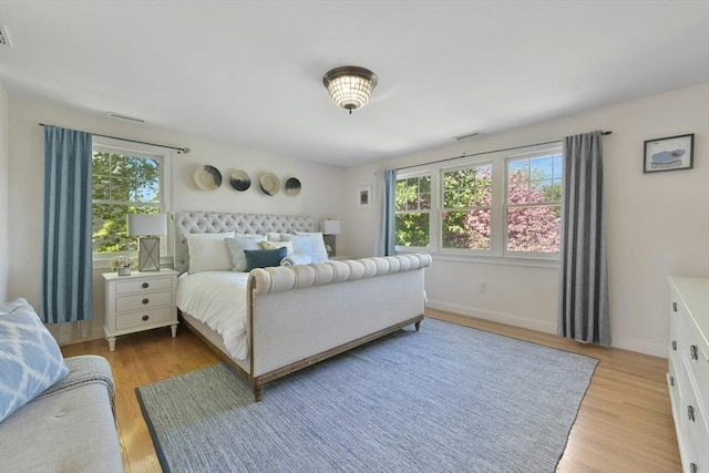 bedroom with multiple windows, light wood-style floors, visible vents, and baseboards
