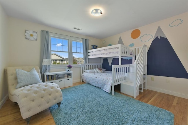 bedroom featuring baseboards, visible vents, and wood finished floors