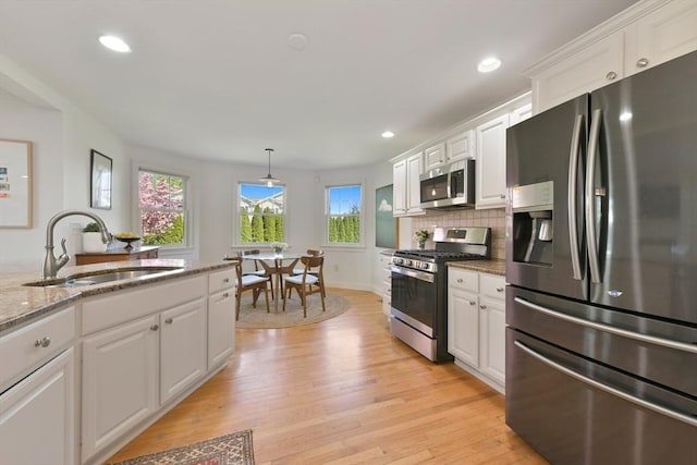 kitchen with light wood finished floors, white cabinets, appliances with stainless steel finishes, and a sink