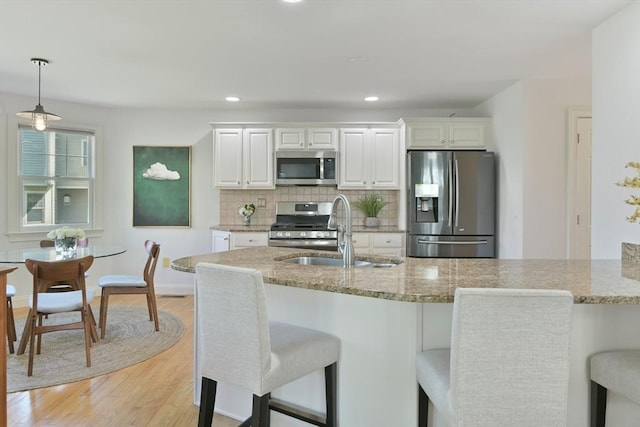 kitchen featuring appliances with stainless steel finishes, light wood-style flooring, a breakfast bar area, and a sink