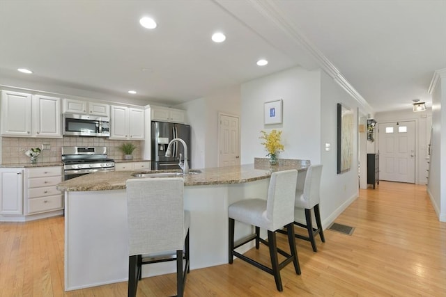 kitchen featuring a peninsula, stainless steel appliances, white cabinetry, and a kitchen breakfast bar