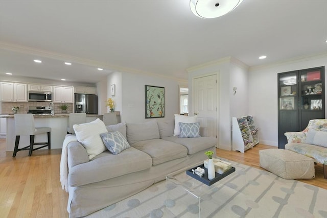 living room with light wood-style floors, ornamental molding, and recessed lighting