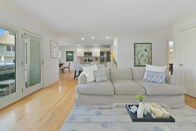 living room with baseboards, ornamental molding, light wood finished floors, and recessed lighting