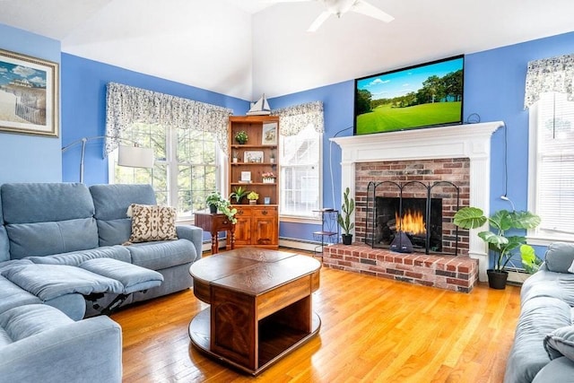 living area featuring vaulted ceiling, a baseboard radiator, a brick fireplace, and wood finished floors