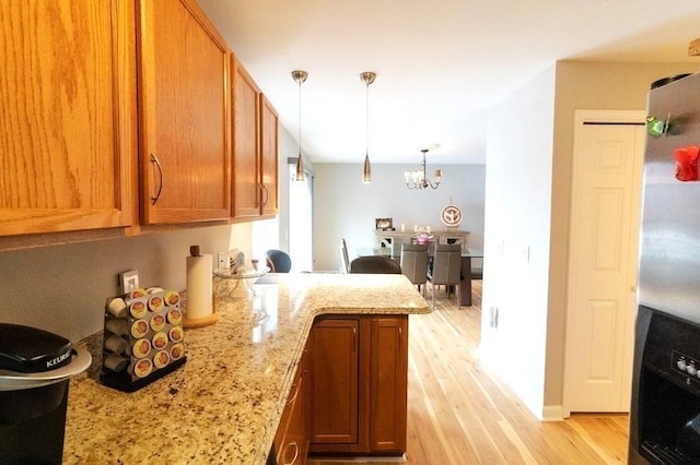 167 Orient St, Worcester, MA 01604 - kitchen featuring stainless steel fridge, light wood finished floors, light stone counters, brown cabinetry, and a peninsula