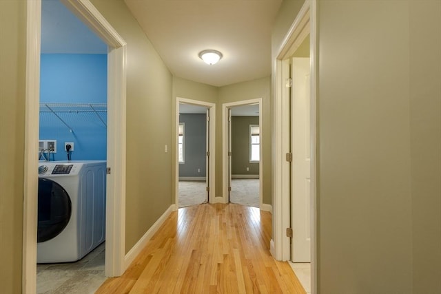 hallway with light wood-style floors, baseboards, and washer / clothes dryer