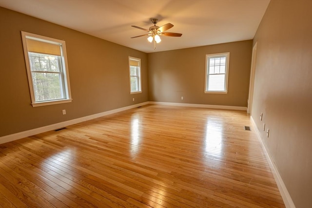 unfurnished room featuring light wood-style floors, visible vents, baseboards, and a ceiling fan