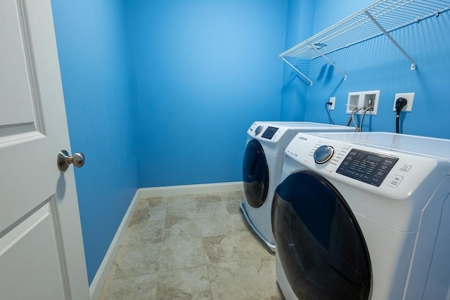 clothes washing area with laundry area, washer and clothes dryer, and baseboards