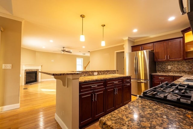 kitchen featuring light wood finished floors, decorative backsplash, a center island, freestanding refrigerator, and a high end fireplace