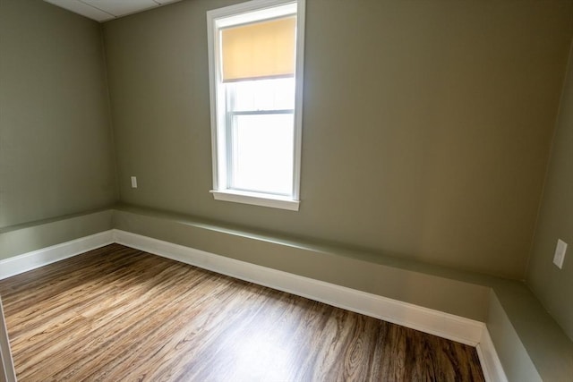 spare room with baseboards and wood finished floors