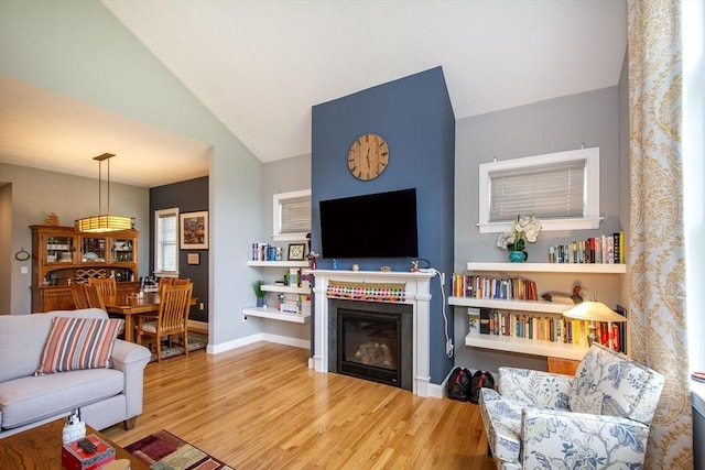 82 Snowbird Ave, Weymouth, MA 02190 - living area with wood finished floors, a glass covered fireplace, and vaulted ceiling
