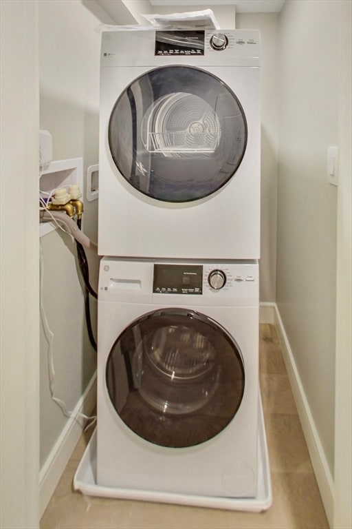 washroom featuring stacked washer / drying machine and light tile patterned floors