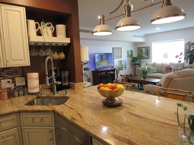 50 S Common St Unit 311, Lynn, MA 01902 - kitchen with a sink, cream cabinets, open floor plan, light stone counters, and decorative backsplash