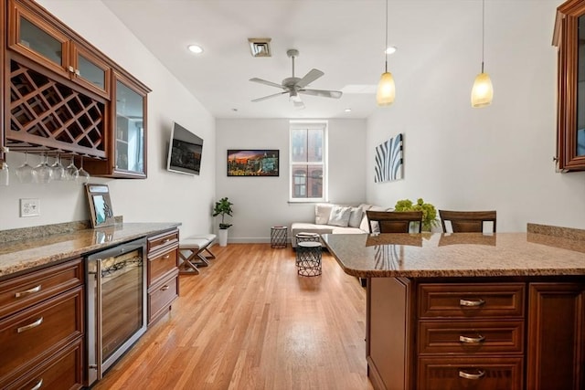 kitchen with glass insert cabinets, a ceiling fan, decorative light fixtures, light wood-type flooring, and wine cooler
