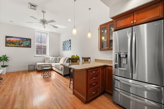 kitchen featuring a peninsula, glass insert cabinets, a breakfast bar area, stainless steel fridge with ice dispenser, and a ceiling fan