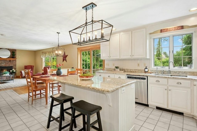 8 Adams Rd, Grafton, MA 01519 - kitchen with stainless steel dishwasher, a sink, light tile patterned floors, a kitchen breakfast bar, and a brick fireplace