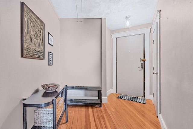 doorway with wood-type flooring, baseboards, and a textured ceiling