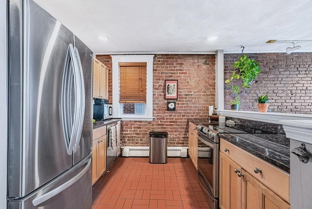 kitchen with appliances with stainless steel finishes, brick wall, brick patterned flooring, a baseboard heating unit, and dark stone countertops