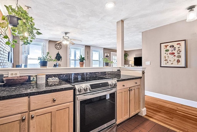 kitchen featuring electric stove, a textured ceiling, light brown cabinetry, baseboards, and ceiling fan