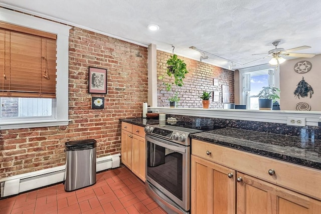 kitchen featuring electric range, brick wall, a ceiling fan, baseboard heating, and dark stone countertops