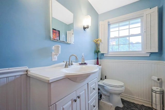 half bath with toilet, wainscoting, and vanity
