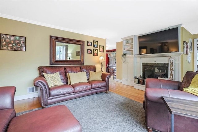 living room featuring wood finished floors, visible vents, a fireplace, and baseboards