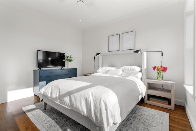 bedroom with a ceiling fan, crown molding, baseboards, and wood finished floors