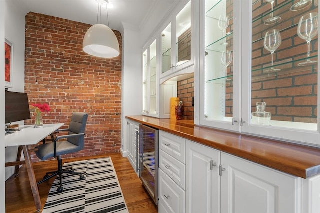 interior space with beverage cooler, light wood-style floors, brick wall, crown molding, and hanging light fixtures