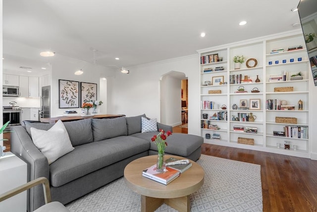 living area with recessed lighting, wood finished floors, arched walkways, and ornamental molding