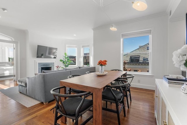 dining space featuring crown molding, a fireplace, and dark wood-style flooring