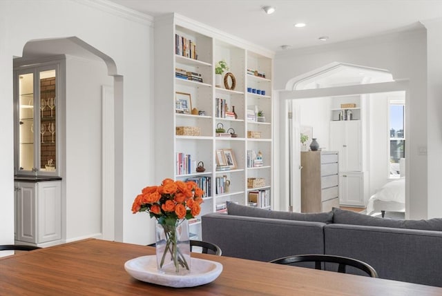 living area with built in features, arched walkways, recessed lighting, and crown molding