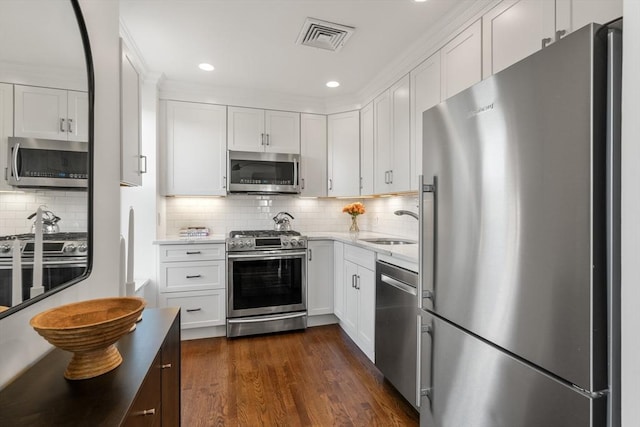 kitchen featuring visible vents, dark wood-style flooring, a sink, appliances with stainless steel finishes, and white cabinetry