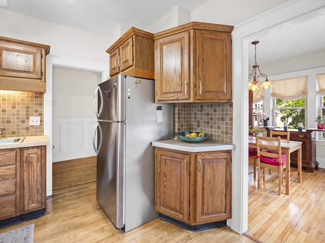 537 Milk St, Fitchburg, MA 01420 - kitchen with freestanding refrigerator, light wood-style floors, brown cabinets, light countertops, and a wainscoted wall