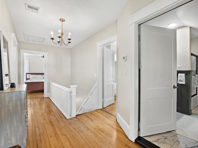 537 Milk St, Fitchburg, MA 01420 - corridor featuring an upstairs landing, a chandelier, baseboards, and light wood-style floors