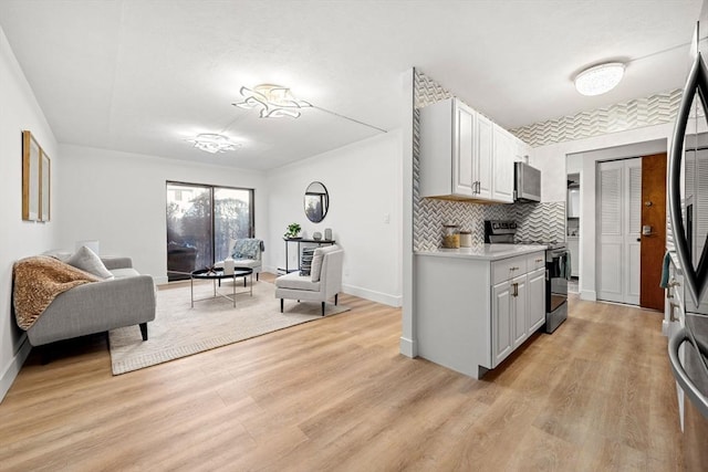 kitchen featuring open floor plan, stainless steel electric range, light countertops, and light wood-style floors