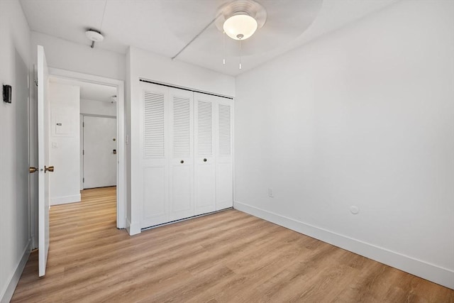 unfurnished bedroom with light wood finished floors, a closet, and baseboards