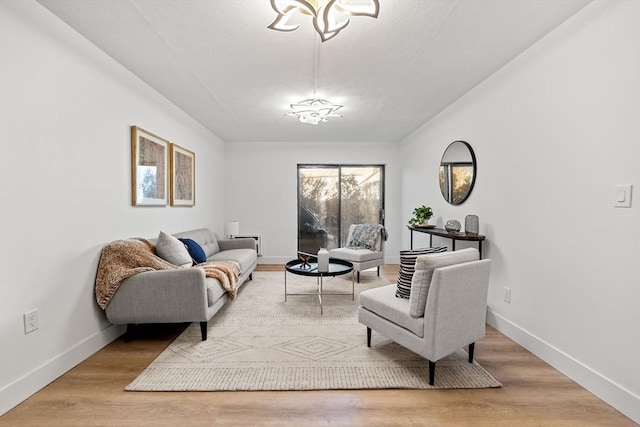 living room featuring baseboards, an inviting chandelier, and wood finished floors