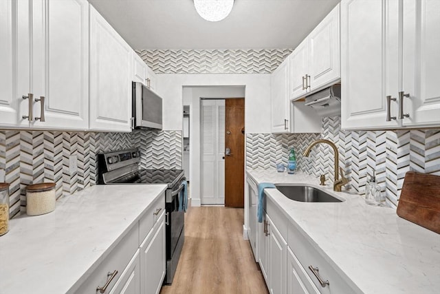 kitchen with stainless steel microwave, range with electric cooktop, light stone counters, white cabinetry, and a sink