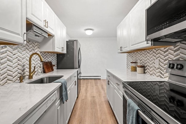 kitchen with a sink, white cabinetry, stainless steel appliances, light wood finished floors, and baseboard heating