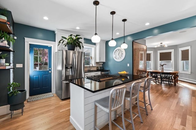 kitchen featuring light wood-style flooring, a kitchen bar, white cabinets, stainless steel fridge with ice dispenser, and dark countertops
