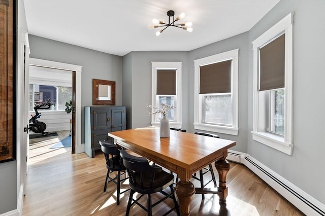dining space with baseboard heating, a chandelier, light wood-type flooring, and plenty of natural light